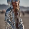 ZEVQ's oversized silver sequin hooded jacket worn at a festival, creating a liquid-metal sparkle effect.