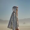 ZEVQ's oversized silver sequin hooded jacket worn at a festival, creating a liquid-metal sparkle effect.