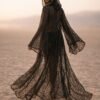 ZEVQ premium black lace hooded kaftan, a sheer festival kimono with gold trim, worn at a desert festival.