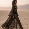 ZEVQ premium black lace hooded kaftan, a sheer festival kimono with gold trim, worn at a desert festival.