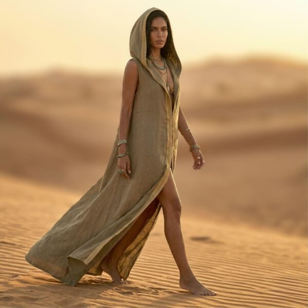 ZEVQ premium khaki linen hooded vest, a maxi festival duster with gold trim, modeled at a desert festival.