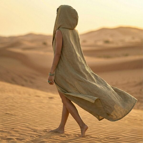 ZEVQ premium khaki linen hooded vest, a maxi festival duster with gold trim, modeled at a desert festival.