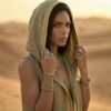 ZEVQ premium khaki linen hooded vest, a maxi festival duster with gold trim, modeled at a desert festival.