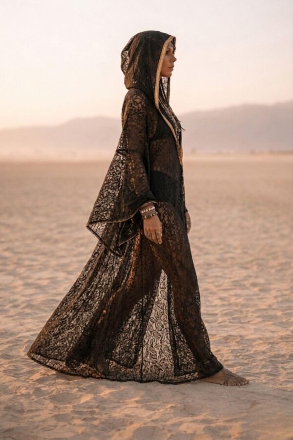 ZEVQ premium black lace hooded kaftan, a sheer festival kimono with gold trim, worn at a desert festival.